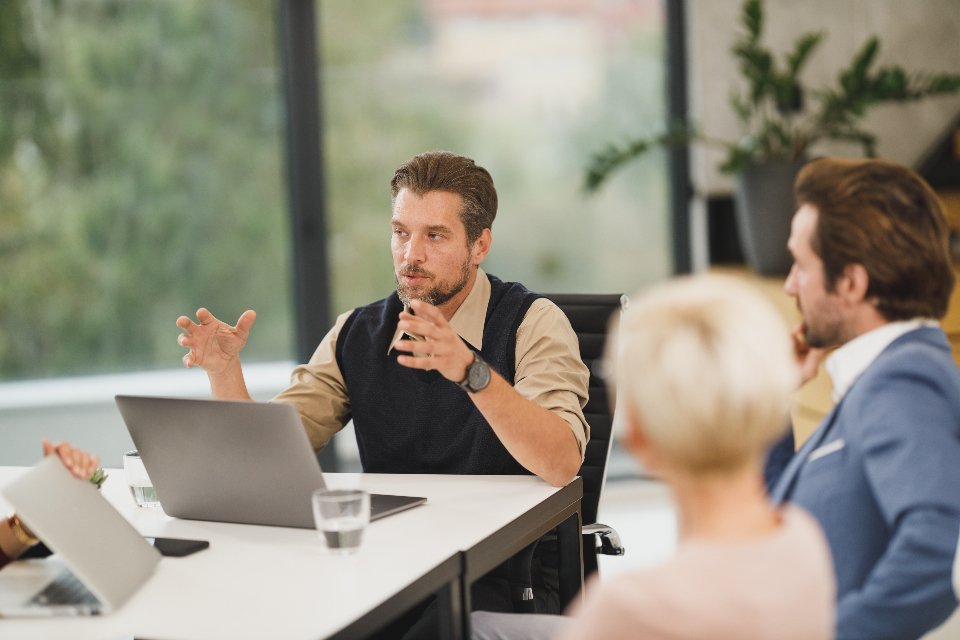 Technology consultants discussing a business solution around a laptop in a modern office