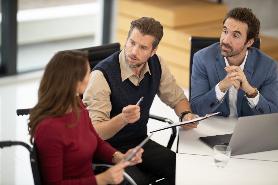 Salesforce consultants collaborating with a client around a laptop in a bright modern office