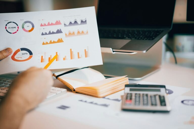 Printed financial charts and graphs beside a laptop
